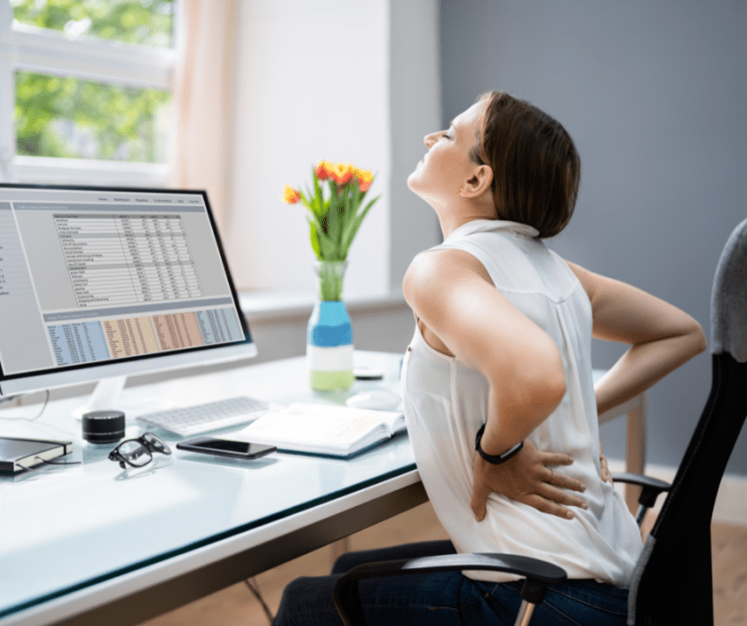 Woman sitting at a desk with lower back pain from bad posture
